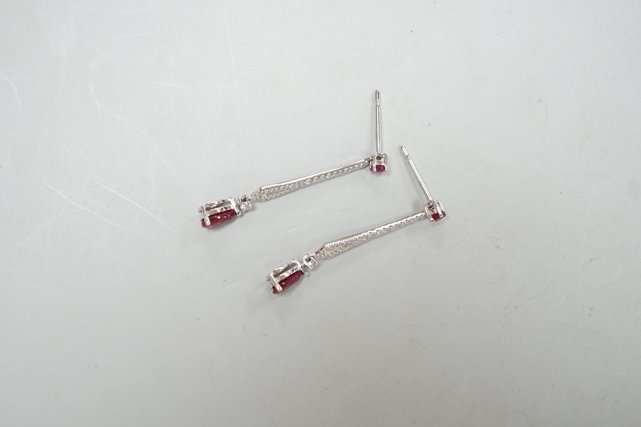 A modern pair of 18k white metal, ruby and diamond cluster set line drop earrings, 30mm, gross weight 2.2 grams.
